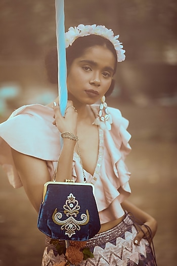 Imbibe retro nostalgia in your appearance with this ruffle-accented lehenga by Bandana Narula. Style the look with a pair of shell bead earrings by Bansri and a clutch by Praccessorii by Quaint Charming